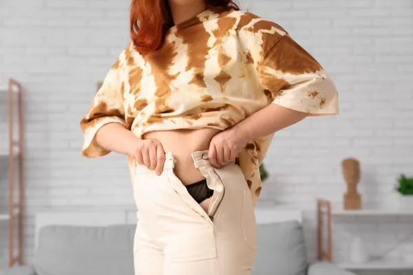 Image of woman trying to do her trousers up after pregnancy weight gain Didcot